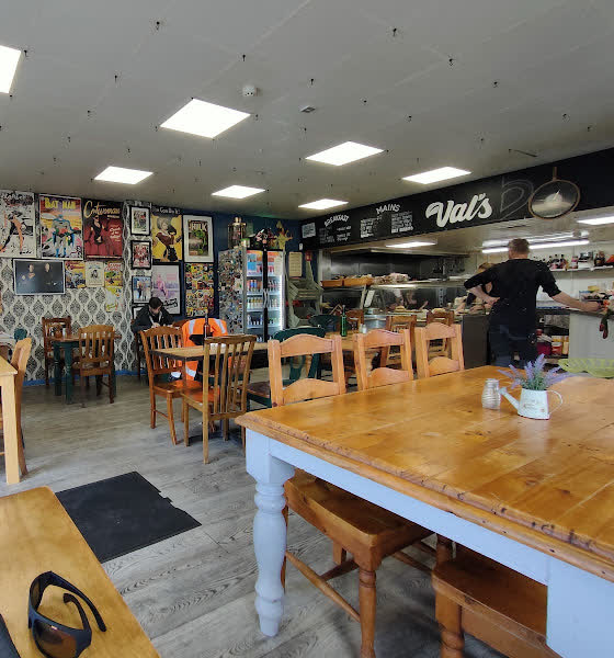 Inside Val’s — wooden tables, chalkboard menus, and the kitchen pass